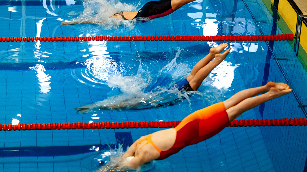 Three women athletes swimmers diving into pool